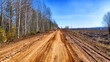 A dry dirt clay rural road in a field, stretching to the horizon in early spring. Rustic landscape