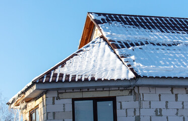 Wall Mural - Roof of a house covered in snow against a blue sky