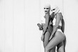Two beautiful sexy women in underwear. Models wearing bandit balaclava mask. Hot seductive female in nice lingerie posing in the street at sunny day. Crime and violence. Perfect body. Black and white