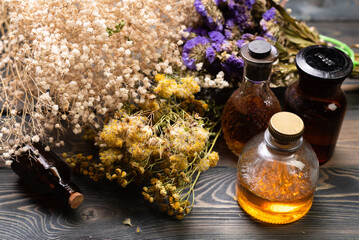 Wall Mural - Herbal medicine concept background. Dry natural ingredients and remedy bottle on the wooden table top view background.