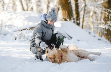 Wall Mural - Teenage Girl Plays With Golden Retriever In Snowy Forest, Sitting With Dog