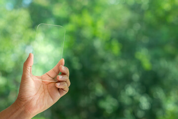 Wall Mural - Hand holding and showing transparent tablet device. Business, natural green bokeh background,technology concept,alternative energy,conservative clean energy .