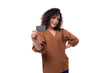 © Ivan Traimak - young fashionista curly brunette woman dressed in a stylish brown blouse shows a plastic card