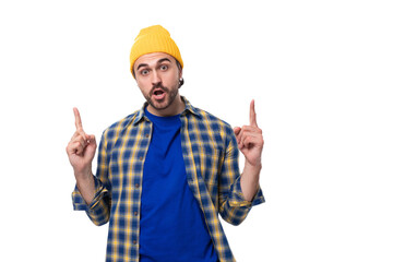 Wall Mural - handsome young hipster man in cap and shirt gesturing actively on white background with copy space