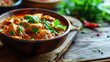 Spicy chicken curry garnished with cilantro in a bowl, with herbs in the background
