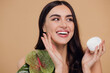 Portrait of charming woman near green flower applying face cream