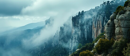 Sticker - Cloudy and foggy weather surrounds cliffs with trees near Montserrat Abbey in Spain.