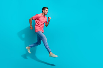 Poster - Full length photo of excited purposeful man wear pink t-shirt speed running jumping high empty space isolated blue color background