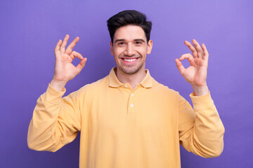 Canvas Print - Photo of toothy good mood guy wear yellow polo smiling showing two okey signs isolated violet color background