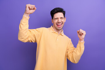 Sticker - Photo of impressed lucky man dressed yellow shirt rising fists shouting yes isolated purple color background