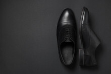 Pair of leather men shoes on black background, top view. Space for text