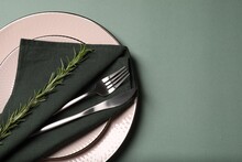 Stylish Table Setting. Plates, Cutlery, Napkin And Rosemary On Green Background, Top View With Space For Text