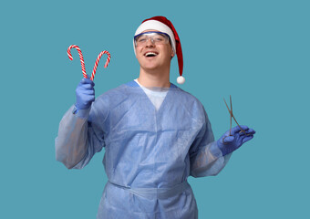 Sticker - Portrait of young male surgeon in Santa hat with candy canes and forceps on blue background