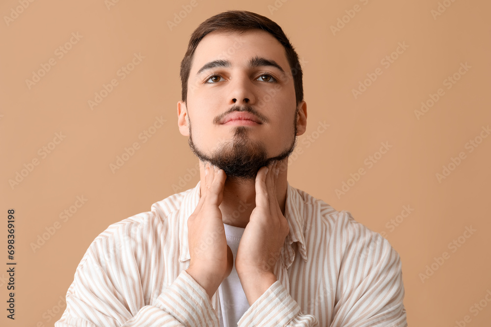 Young man with thyroid gland problem on beige background