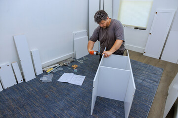 Wall Mural - Carpenter uses screwdriver during installation of closet cabinet