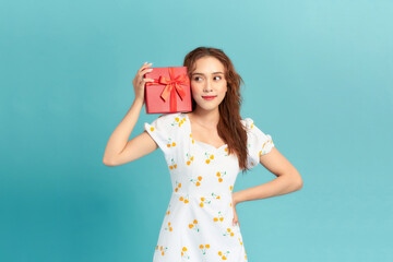 Wall Mural - Portrait of happy charismatic girl shaking gift box wondering whats inside as celebrating birthday