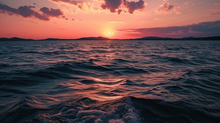 water in the sunset at an ocean level with a sailboat coming