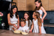 © dvulikaia - Young mother cooks  sweet cottage cheese pie with her daughters. Mom teaches her daughters to cook.