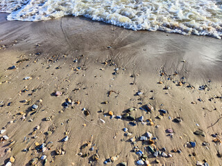 Wall Mural - Yellow sand, pebbles and a transparent wave as a background, texture. Abstract pattern, place for text, copy space