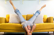 Happy and joyful adult woman lay down on the sofa in reverse position with legs up and head down smiling and having fun at home - middle age young lady active lifestyle laughing a lot on the couch