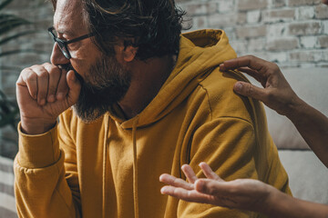 Sad and worried man looking away while woman touching his shoulder trying to speak with him. Couple and love problems. Bad relationship moment. People and depression. Husband and wife problem at home