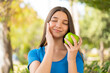 © luismolinero - Teenager girl at outdoors holding an apple with happy expression