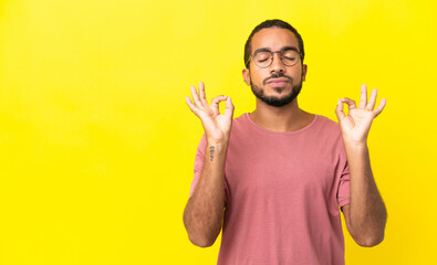 Sticker - Young latin man isolated on yellow background in zen pose