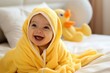 A happy laughing child in a yellow duck towel with a hood