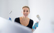 Beautiful blonde woman is having fun, sticking out her tongue while painting