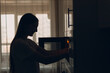 © primipil - A housewife woman cooks food and looks into the oven in the kitchen.