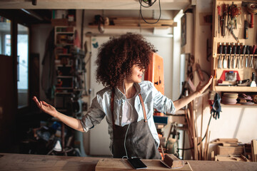 Young woman listening to music in wood workshop