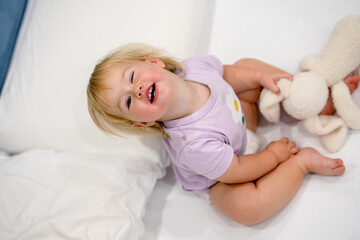 Wall Mural - Cute caucasian blonde baby child on white sheets on the bed