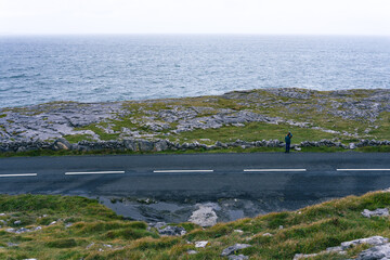 Wall Mural - View of a lonely road with sea in the background from the top of a hill in County Clare in Ireland