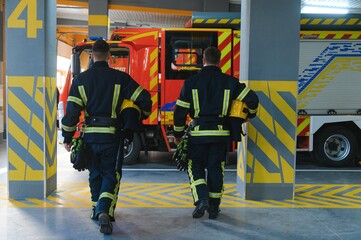 Wall Mural - Portrait of two young firemen in uniform standing inside the fire station