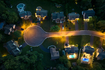 Residential illuminated homes at night in suburban sprawl development in Rochester, New York. Low-density two story private houses in rural suburbs. Housing market in the USA