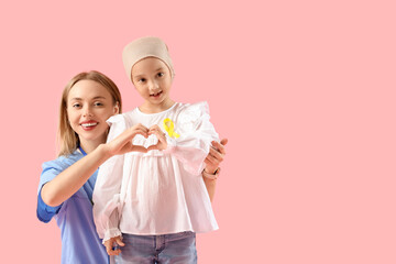 Sticker - Little Asian girl after chemotherapy with nurse making heart gesture on pink background. Childhood cancer awareness concept