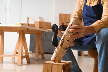 Mature carpenter chopping wood in workshop, closeup