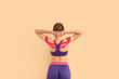 Young woman with physio tape on beige background, back view