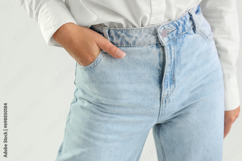 Young woman in trendy jeans on light background, closeup