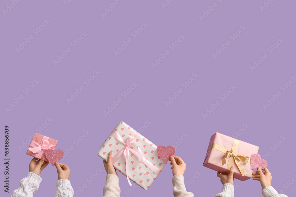 Female hands with gift boxes and hearts on lilac background. Valentine's Day celebration