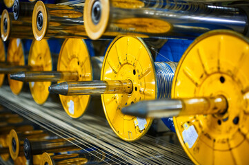 Yellow bobbins and metal spools in production workshop