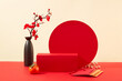 A red podium is displayed with a vase of peach blossoms, tangerines and lucky money envelopes. Beige and red background. Space for Tet advertising.