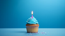 Birthday Cupcake With One Candle On Blue Background And Sprinkles