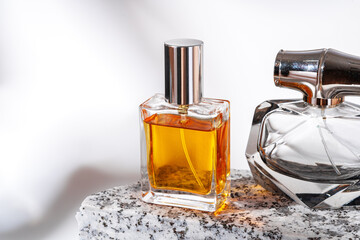 Perfume bottle on granite stones against white background with shadows