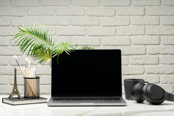 Canvas Print - Laptop with black screen on desk against white brick wall