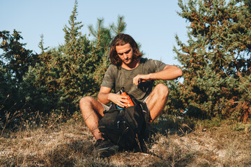 Man hiker sitting on rock resting during trekking in the countryside