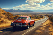 Vintage red sports car rides an empty mountain highway on a sunny day, rear view
