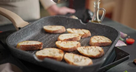 Wall Mural - making grilled bruschetta bread - sliced baguette pieces on grill frying pan