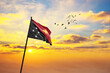 Waving flag of Papua New Guinea against the background of a sunset or sunrise. Papua New Guinea flag for Independence Day. The symbol of the state on wavy fabric.
