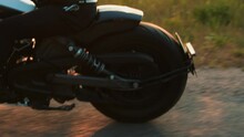 Side View Of Rear Wheel Of Motorcycle Traveling At High Speed On Dirt Road. Close-up